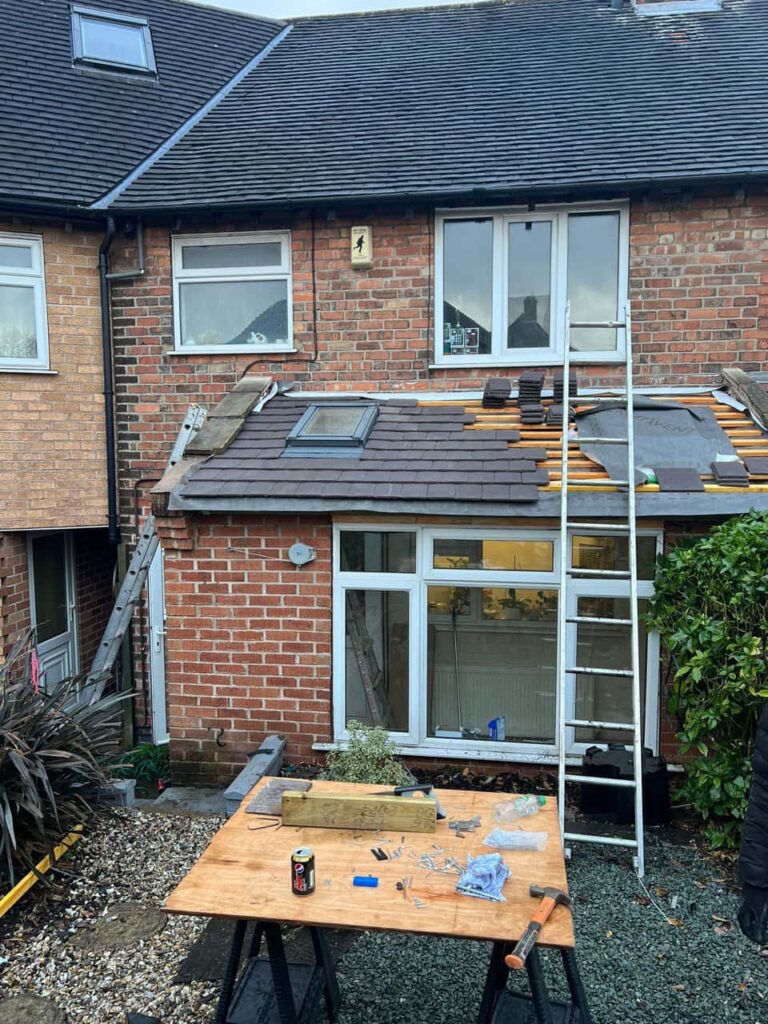 This is a photo of a roof extension that is having new roof tiles installed. This is a photo taken from the roof ridge looking down a tiled pitched roof on to a flat roof. Works carried out by Haddenham Roofing Repairs