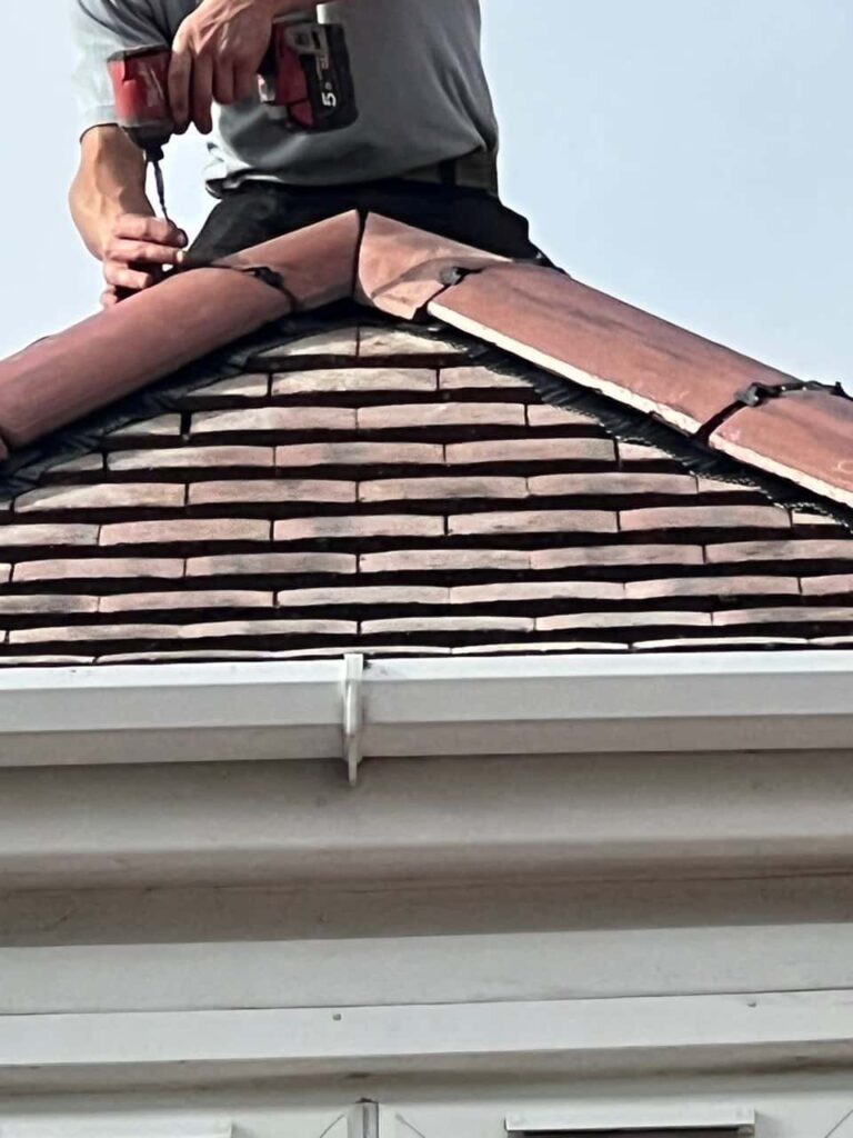 This is a photo of one of the operatives of Haddenham Roofing Repairs installing new ridge tiles