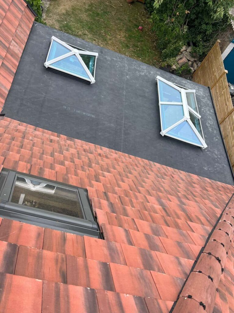 This is a photo taken from the roof ridge looking down a tiled pitched roof on to a flat roof. Works carried out by Haddenham Roofing Repairs